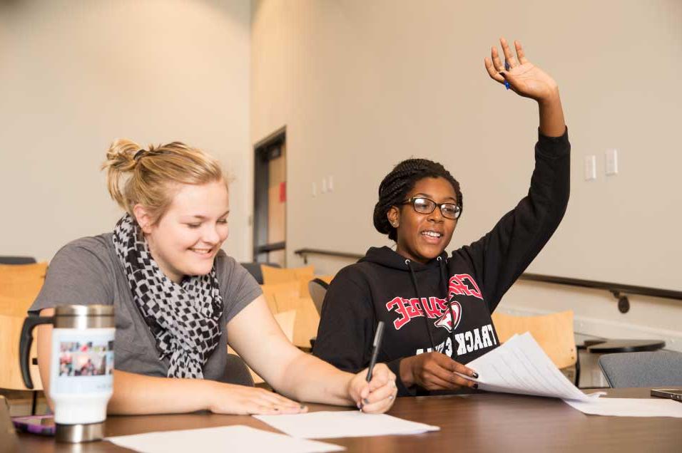 Student raising their hand in a classroom.