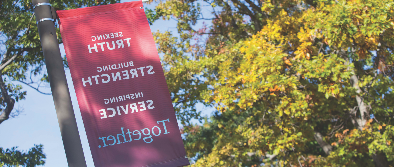 A banner on Campus Drive displays the Carthage College mission statement: Seeking Truth, Building...